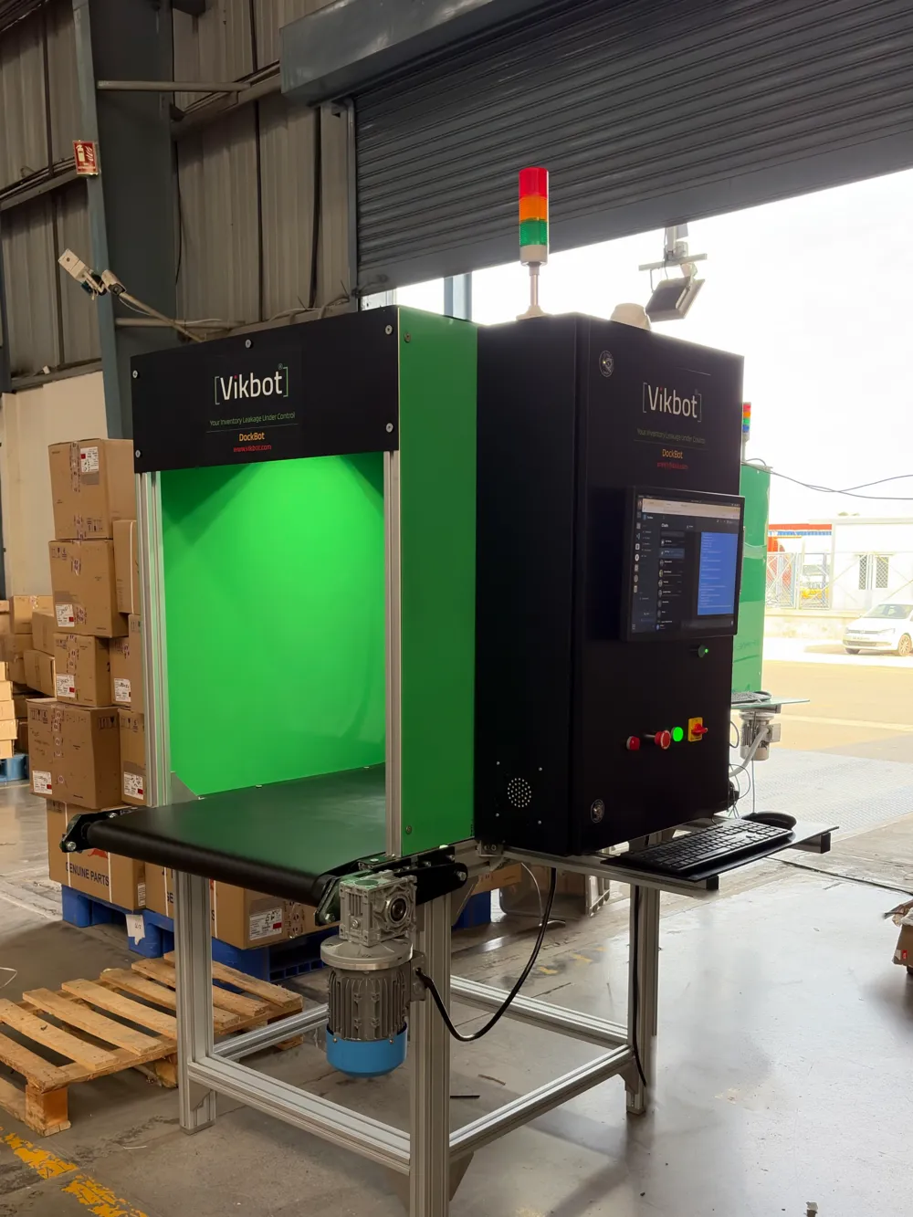Vikbot DockBot installed at a warehouse loading dock, with conveyor, scanning booth, signal tower and touchscreen
